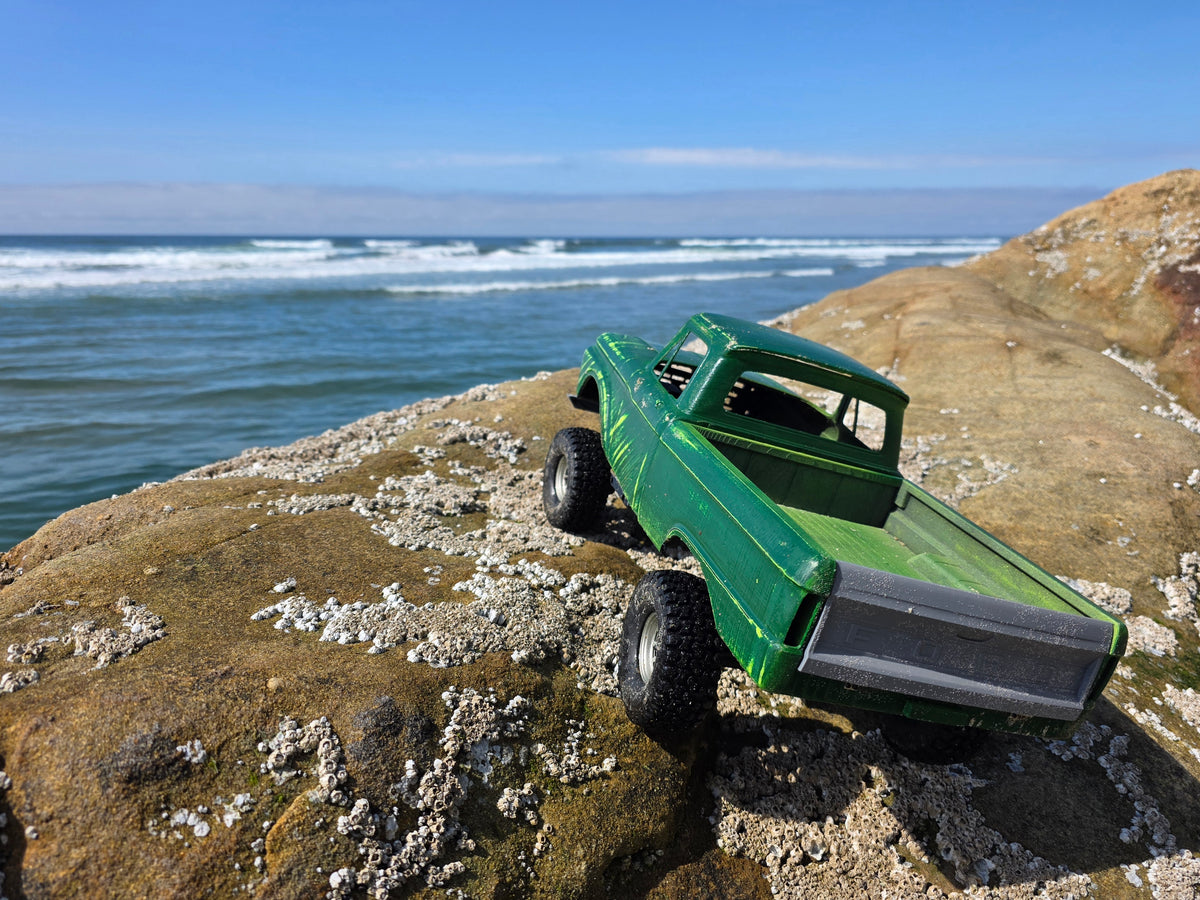 1963-66 Ford F100 painted RC body and mounts on BBV5 chassis, articulating over coastal rocks with ocean in background